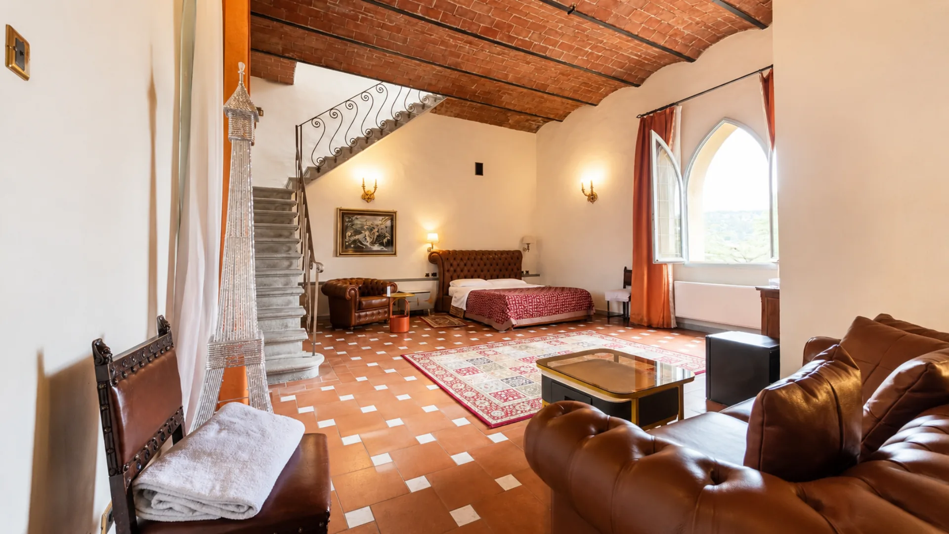 Una King deluxe con la volta in mattoni, la scala in pietra al soppalco e la finestra ad arco gotico